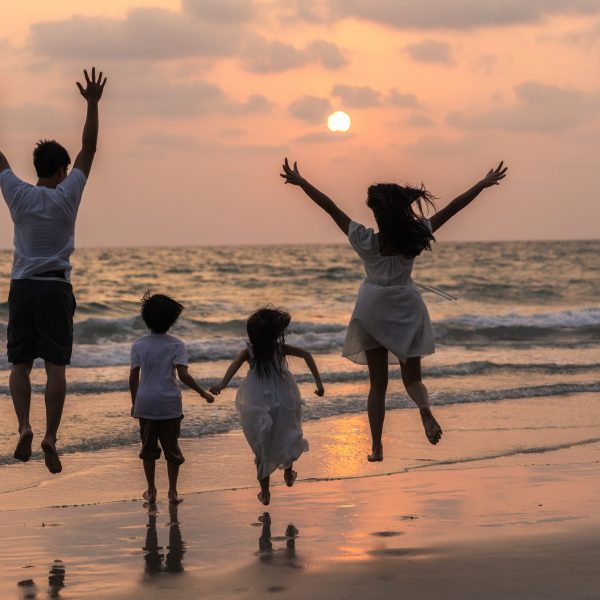 Asian young happy family enjoy vacation on beach in evening. Dad, mom and kid relax running together near sea while silhouette sunset. Lifestyle travel holiday vacation summer concept.